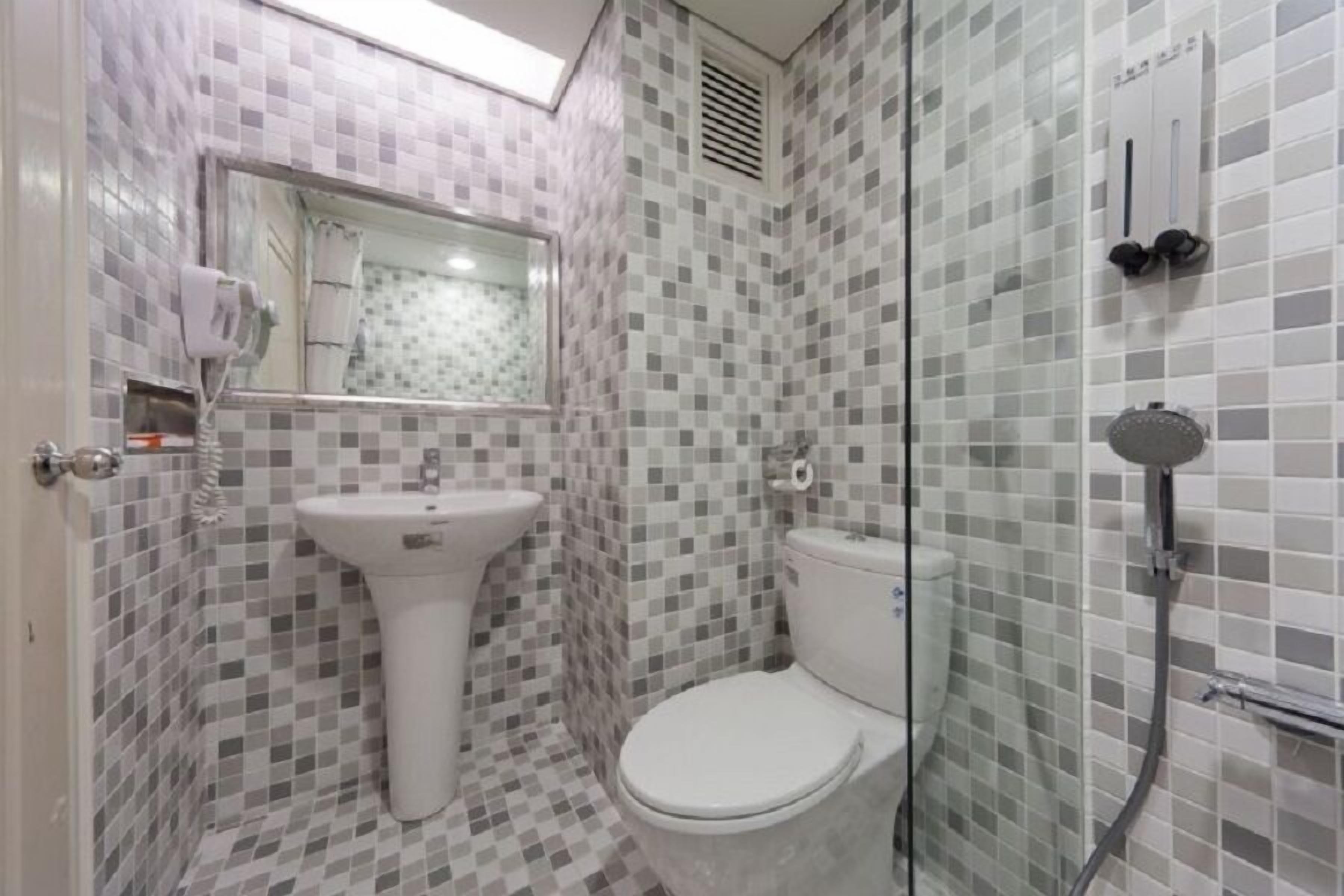 A bathroom with a tiled floor, a sink, a toilet, and a glass-enclosed shower area.
