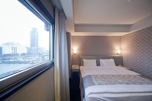 Enjoy a city view from the comfort of this stylish room, featuring a large window and a neatly made bed.