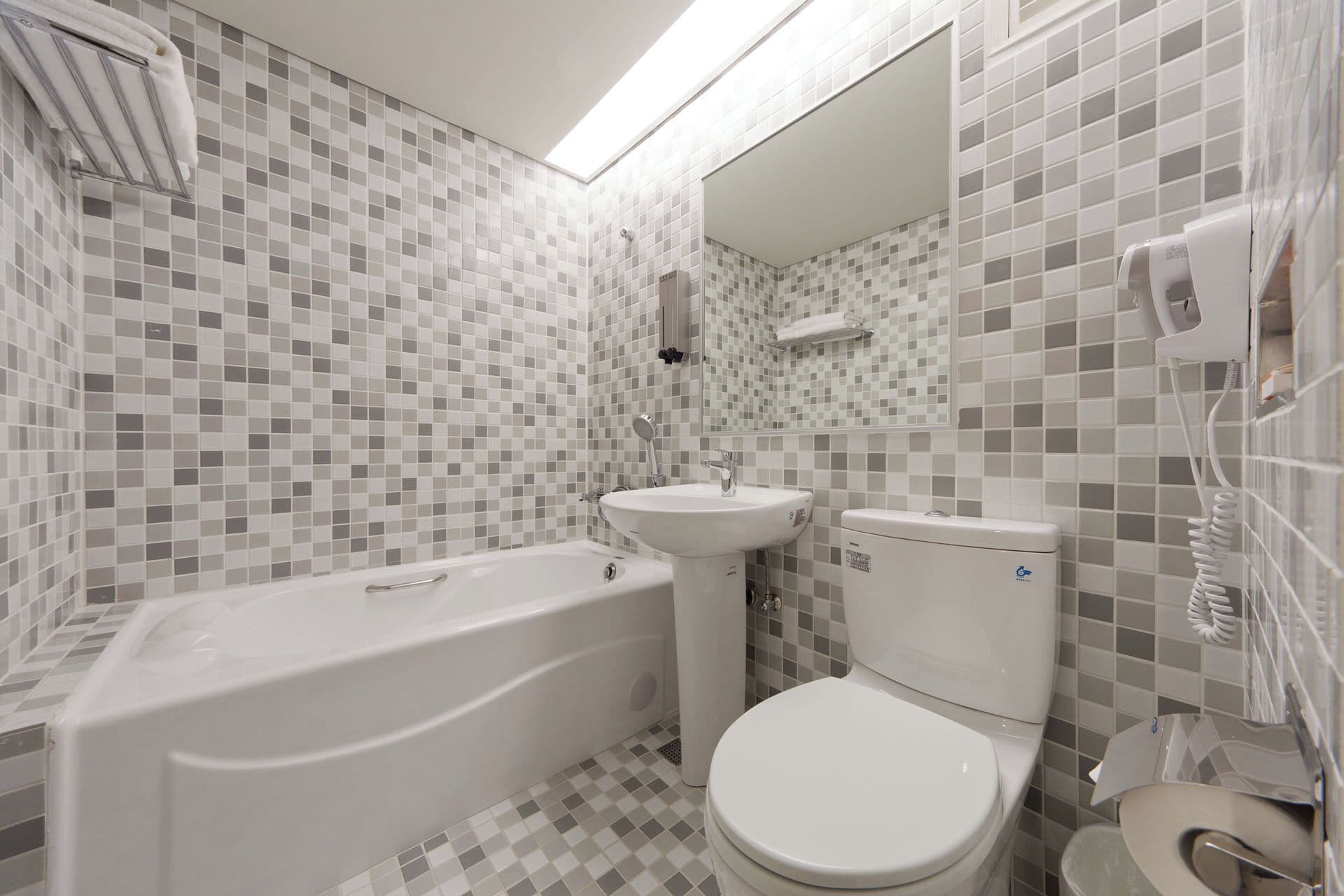 Een badkamer met bad, wastafel, toilet en douchekop.