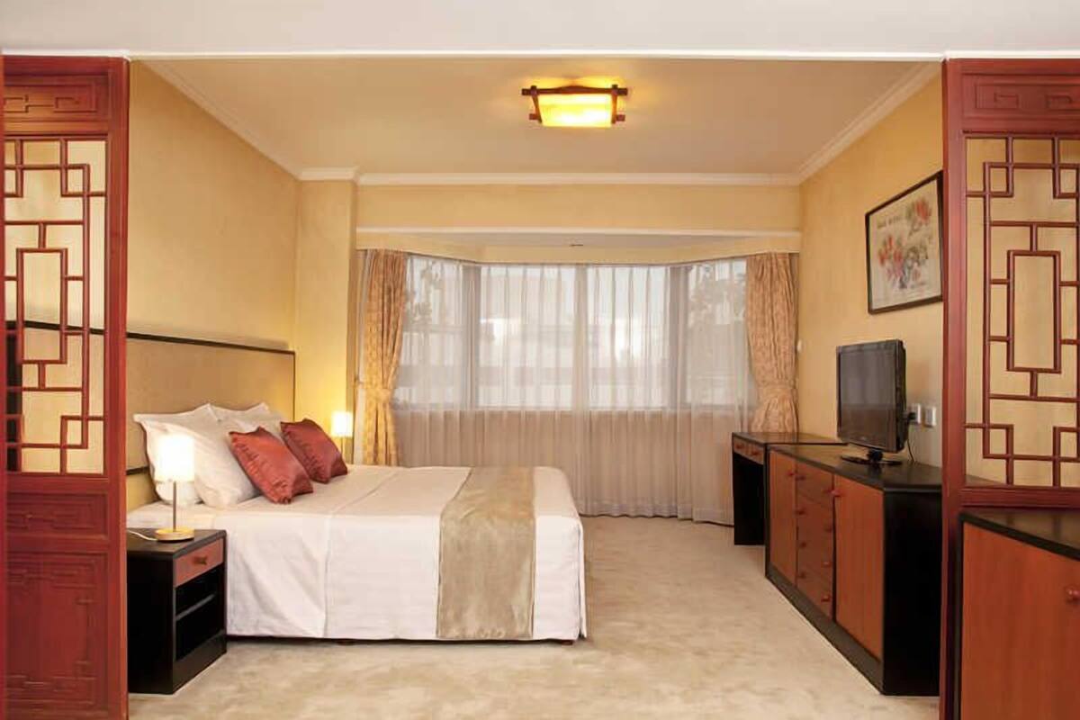 Une chambre d’hôtel comprenant un lit, une table de chevet, une télévision et un bureau avec des tiroirs.