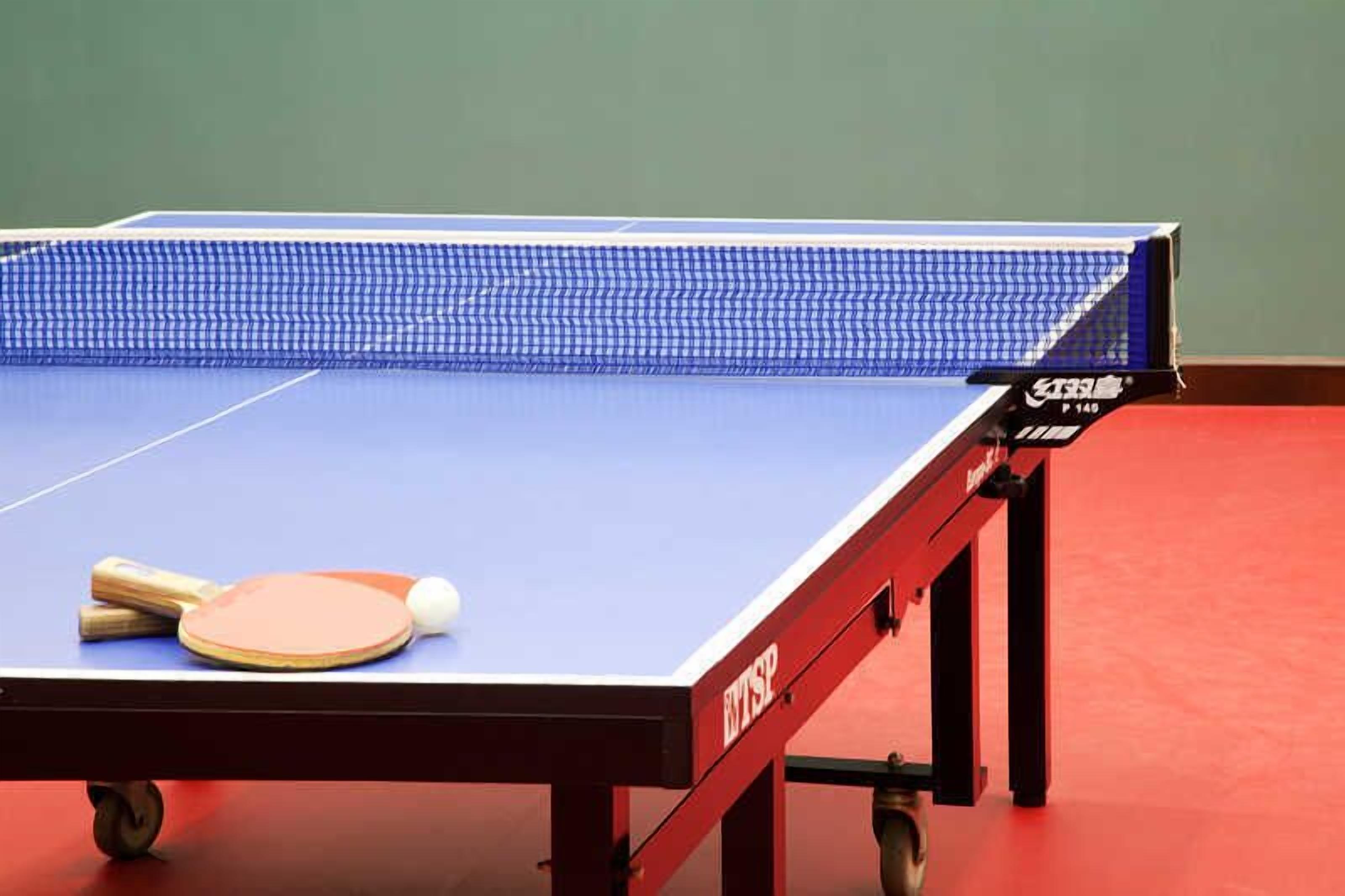 A table tennis table with a blue playing surface and a net.