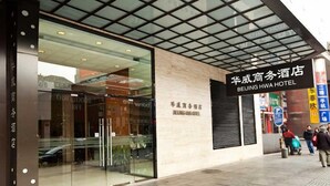 The exterior of Beijing Hwa Hotel with a modern facade, large glass entrance, and a signboard displaying the hotel name. - Beijing HWA Apartment Hotel (Beijing)