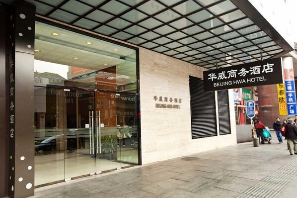Exterior del Hotel Beijing Hwa, con una fachada moderna, una entrada de cristal amplia y un cartel con el nombre del hotel.