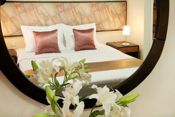 Een hotelkamer met een bed, nachtkastje, lamp en een spiegel.