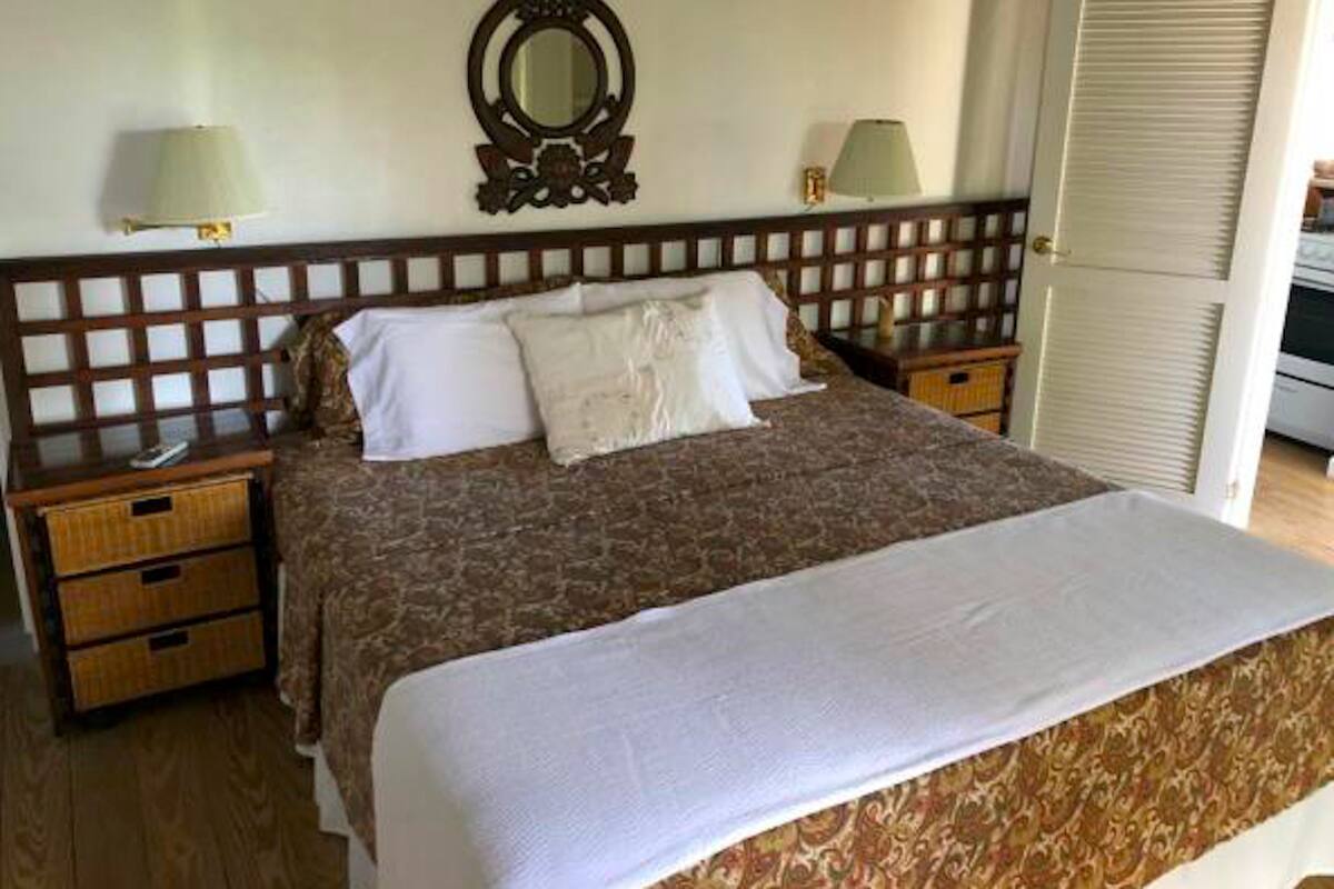 Een slaapkamer met een groot bed, twee nachtkastjes, een spiegel en een kledingkast.