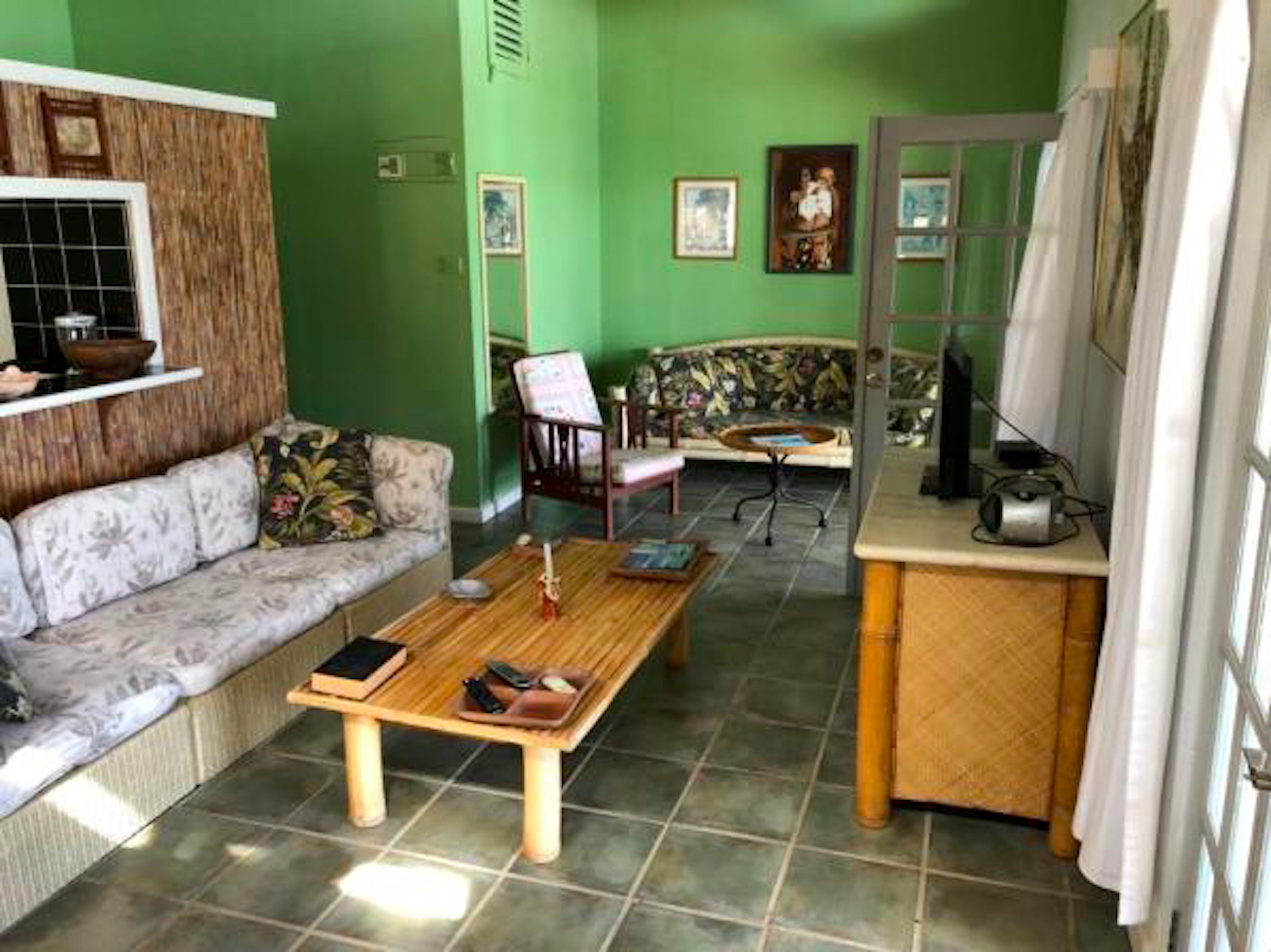 A living room with a sofa, a coffee table, a chair, and a small table with a radio.