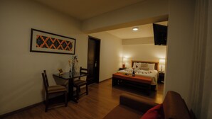 Ein Hotelzimmer mit Bett, Nachttisch, Lampe und einem Essbereich mit Tisch und Stühlen.
