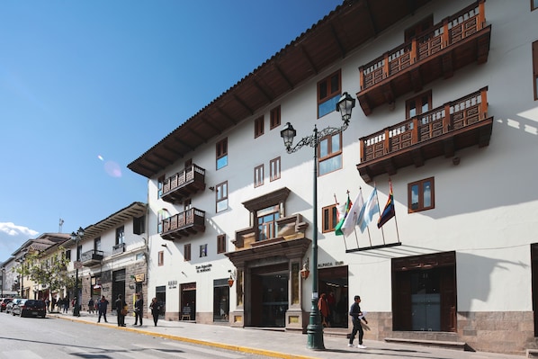 Calle con edificios, incluyendo un hotel con balcones y banderas.