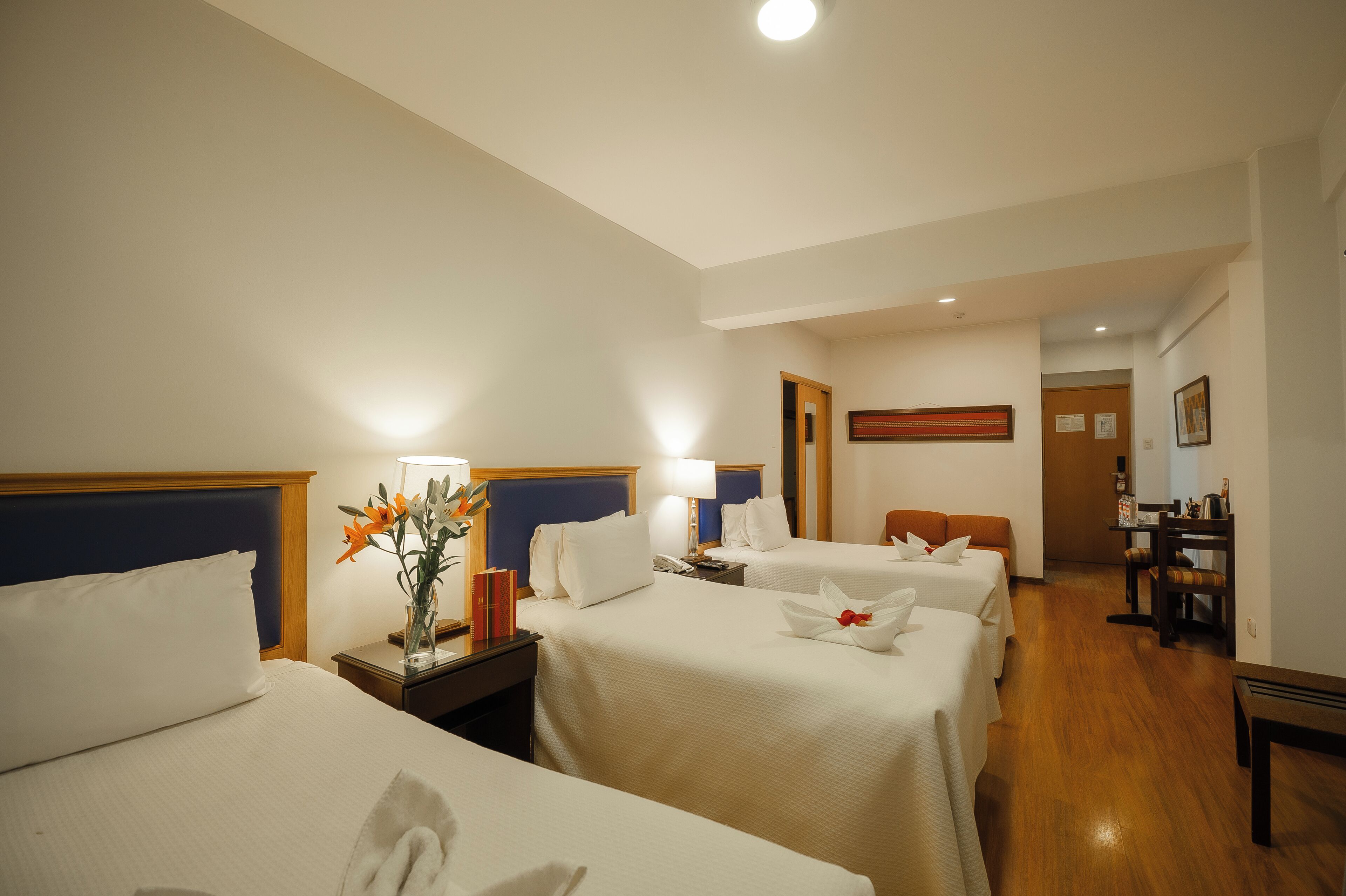 Habitación de hotel con dos camas, un escritorio, una silla y un comedor.