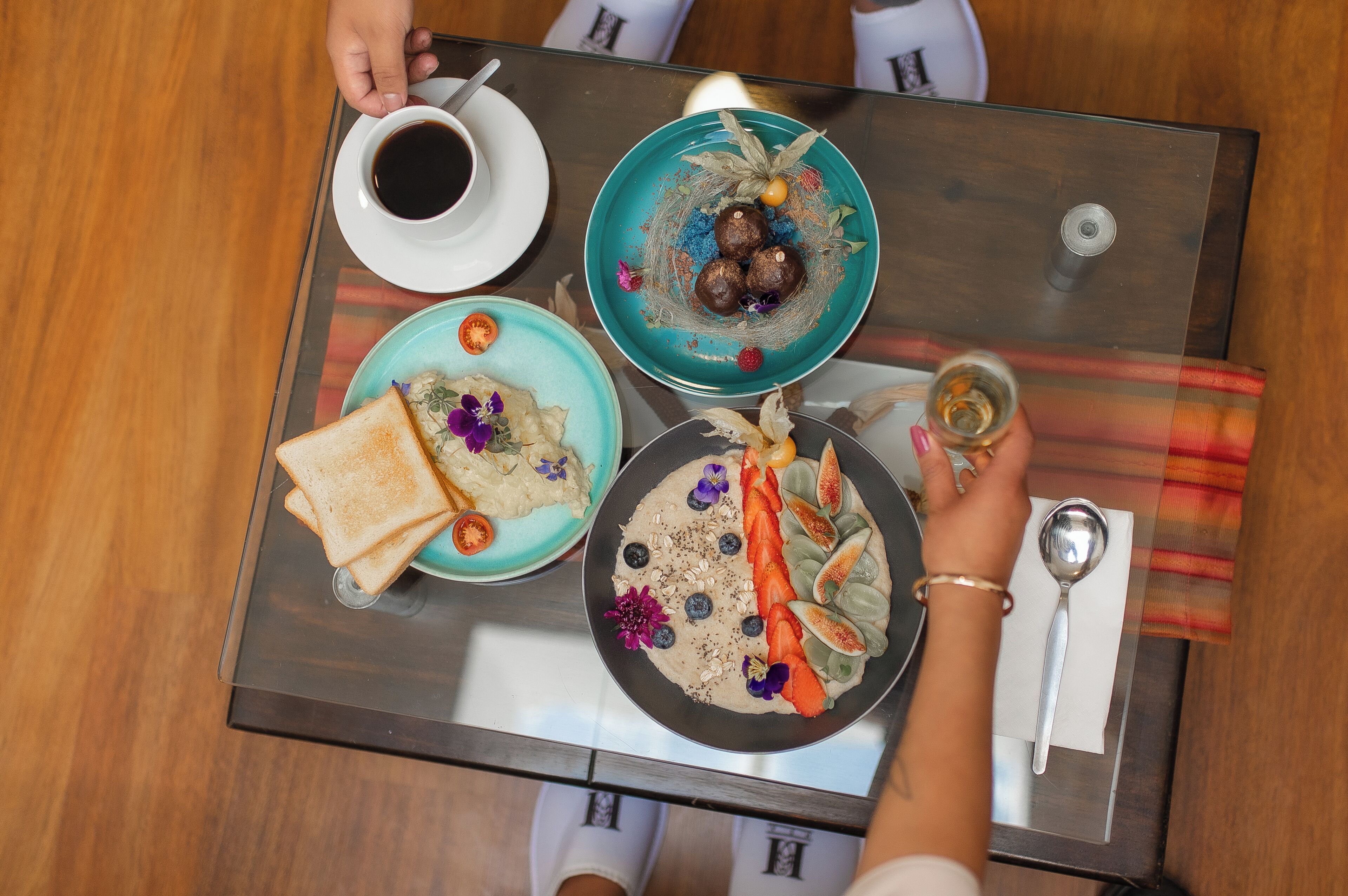 Una mesa con diversos alimentos, incluyendo tostadas, un tazón de sopa y un plato con frutas y semillas.