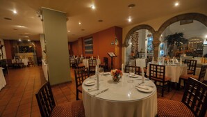 Un restaurante con mesas redondas, sillas y suelo de baldosas.