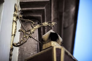 Una ornamentada estructura metálica fijada a la pared, probablemente parte del exterior de un edificio.