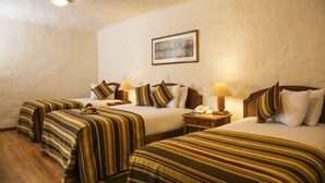 A hotel room with two beds, striped bedding, bedside lamps, a framed picture on the wall, and a wooden floor. - San Agustin Internacional Hotel (Cusco)