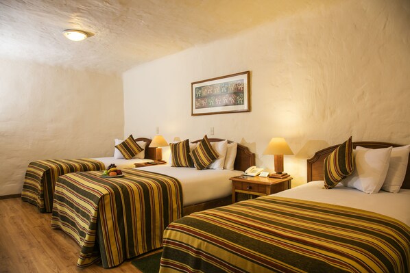 A hotel room with two beds, striped bedding, bedside lamps, a framed picture on the wall, and a wooden floor.