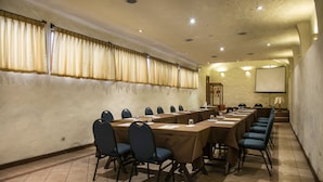 A conference room with long tables, chairs, and a projector screen. - San Agustin Internacional Hotel (Cusco)