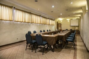 A conference room with long tables, chairs, and a projector screen.
