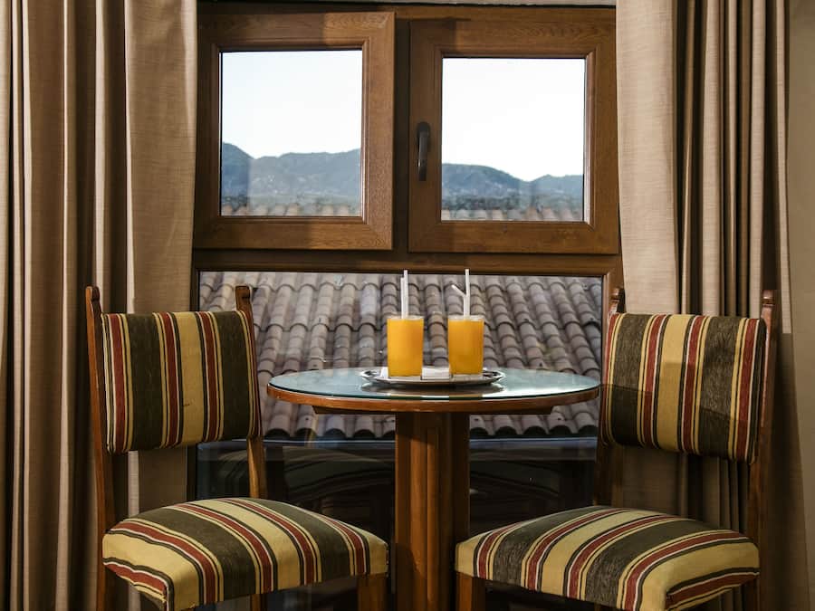 Un comedor con dos sillas a rayas, una mesa redonda y dos vasos de jugo de naranja.