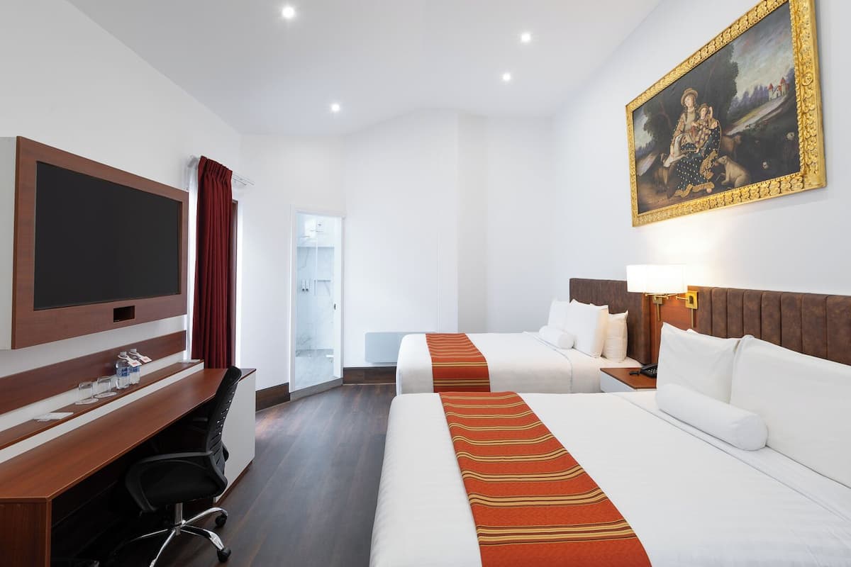 A hotel room with two beds, a desk, a TV, and a painting.