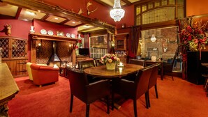 Una habitación acogedora con una mesa de comedor de madera, alfombra roja y un candelabro.