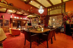 Una habitación acogedora con una mesa de comedor de madera, alfombra roja y un candelabro.