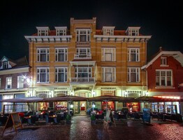 Un hotel con restaurante y bar en la planta baja, que presenta fachada de ladrillo y varias ventanas.
