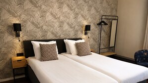 A double bed with two pillows, a nightstand, a wall-mounted lamp, and a mirror. - Paping Hotel & Spa by Flow (Ommen)