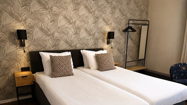A double bed with two pillows, a nightstand, a wall-mounted lamp, and a mirror. - Paping Hotel & Spa by Flow (Ommen)