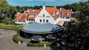 A hotel with a central courtyard, outdoor seating, and a red-tiled roof. - Paping Hotel & Spa by Flow (Ommen)