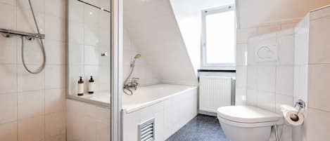 Un baño moderno con cabina de ducha de vidrio, bañera y retrete.