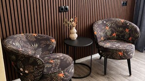 A room with two armchairs and a small table, wooden slatted wall, and a vase with dried flowers. - Paping Hotel & Spa by Flow (Ommen)