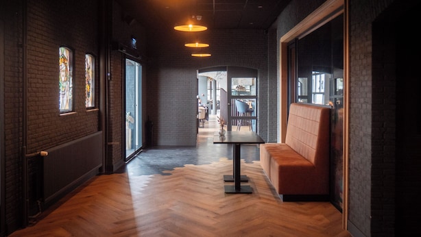A corridor with wooden flooring, a bench, and hanging pendant lights. - Paping Hotel & Spa by Flow (Ommen)
