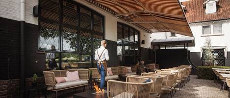 An outdoor seating area with wicker furniture, a fire feature, and a covered patio.