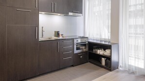 Una cocina moderna con armarios de madera oscura, electrodomésticos de acero inoxidable y un ventanal con cortinas de gasa.