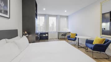 A modern hotel room with a large bed, a desk, two chairs, and a dining table.
