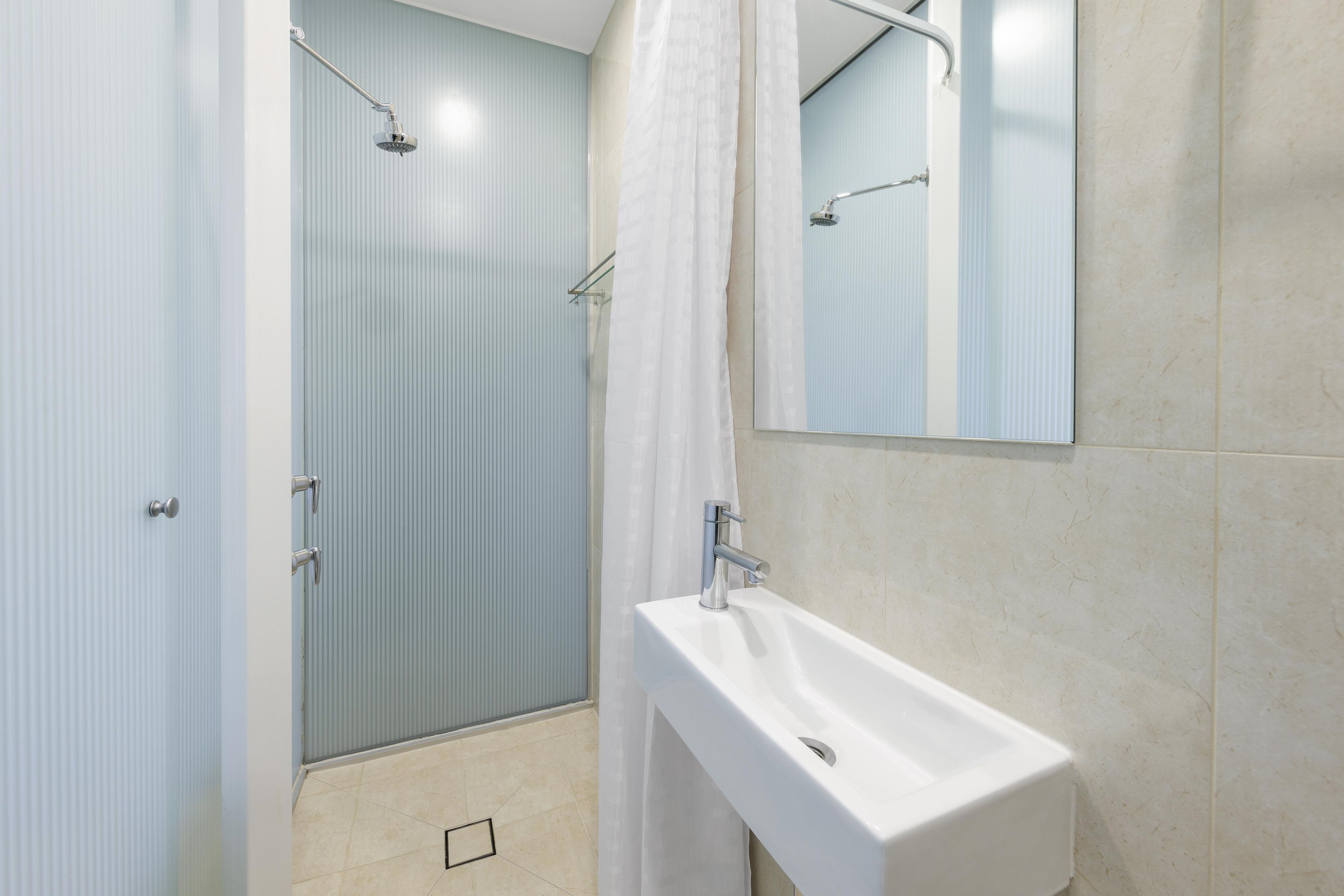 A bathroom with a shower, a sink, and a mirror.