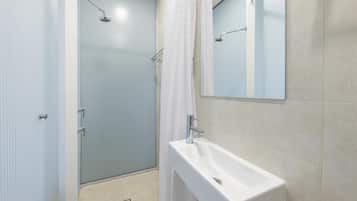 A bathroom with a shower, a sink, and a mirror.