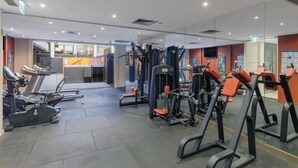 A gym with exercise equipment, a treadmill, and a mirrored wall.