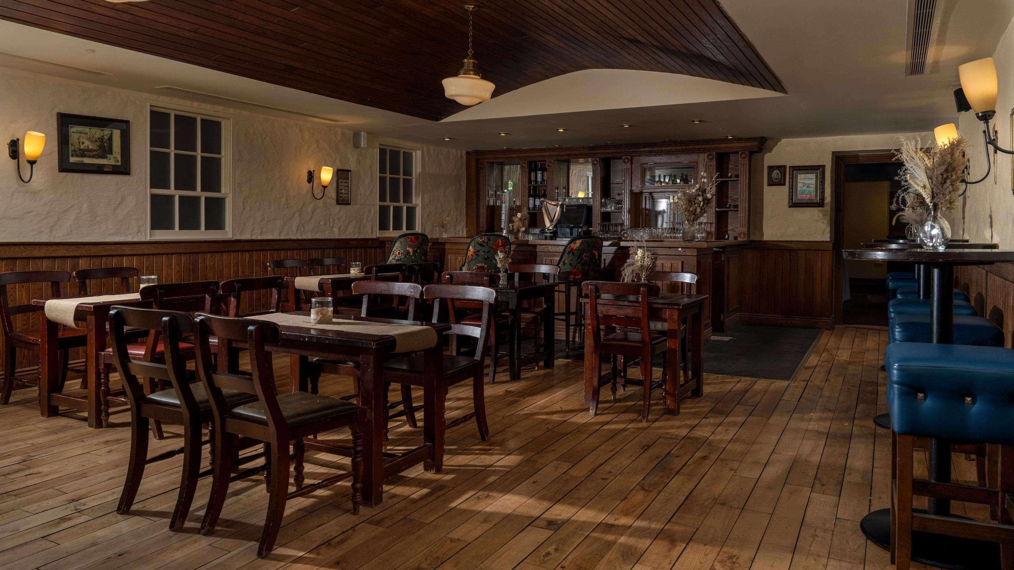 A restaurant with wooden tables and chairs, a bar area, and a wooden ceiling.