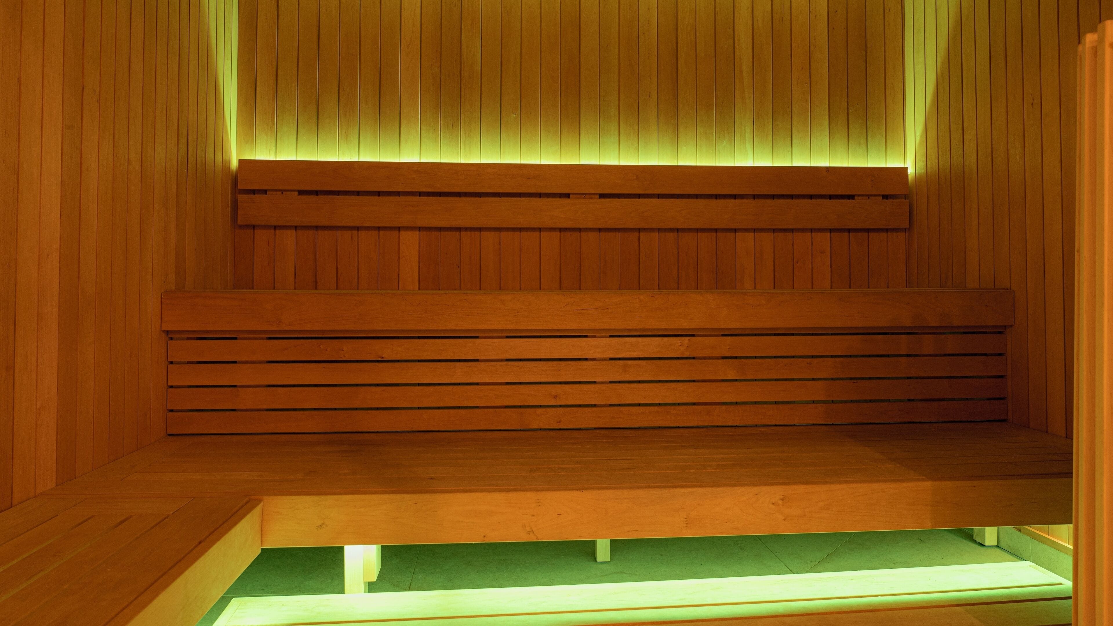 A wooden sauna with benches and a green floor.