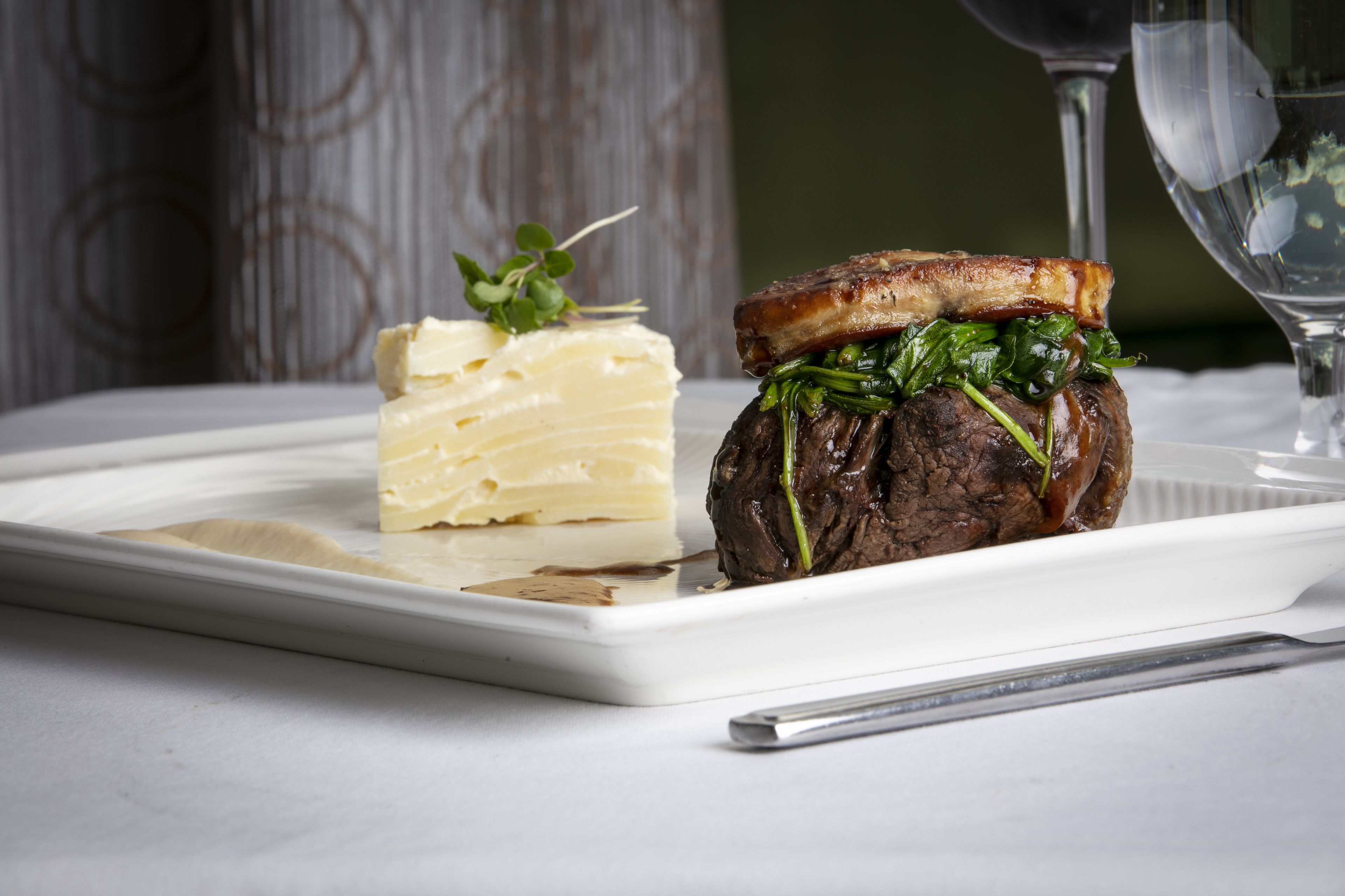 Une assiette blanche rectangulaire sur laquelle on voit un sandwich au steak et une part de tarte.