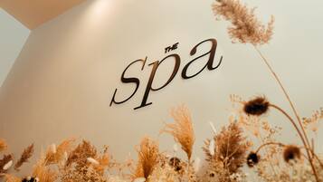 A wall with the words "The Spa" in a stylized font, surrounded by dried flowers.