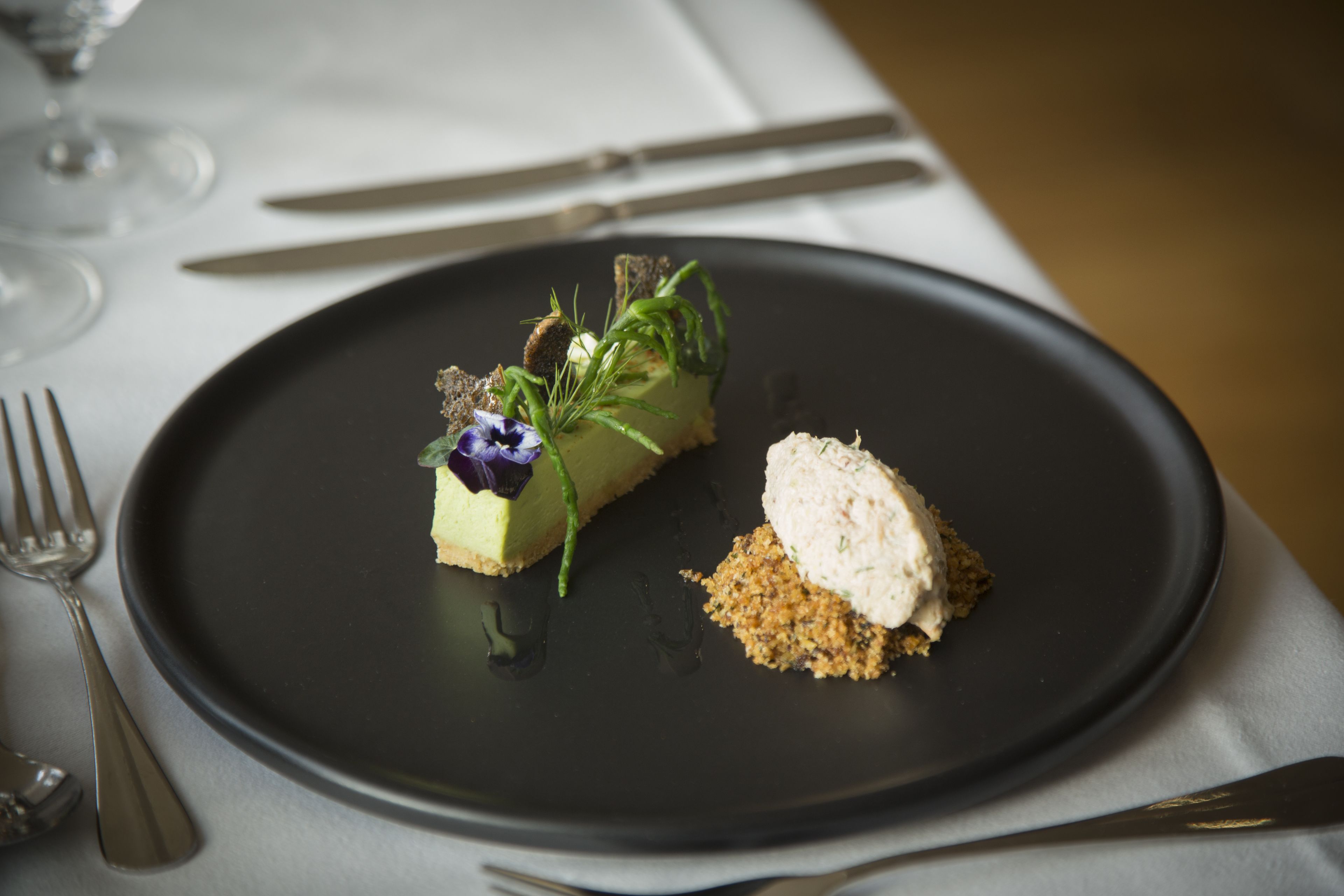 A dessert plate with a slice of cake and a scoop of ice cream, accompanied by a small pile of crumbled biscuit.