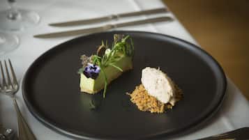 A dessert plate with a slice of cake and a scoop of ice cream, accompanied by a small pile of crumbled biscuit.