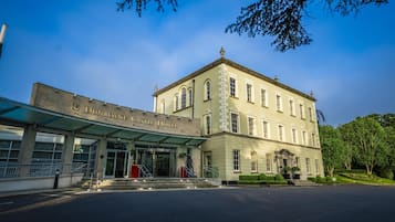 Das Hotel Dunboyne Castle mit überdachtem Eingang, einer Statue und einem gepflegten Rasen.