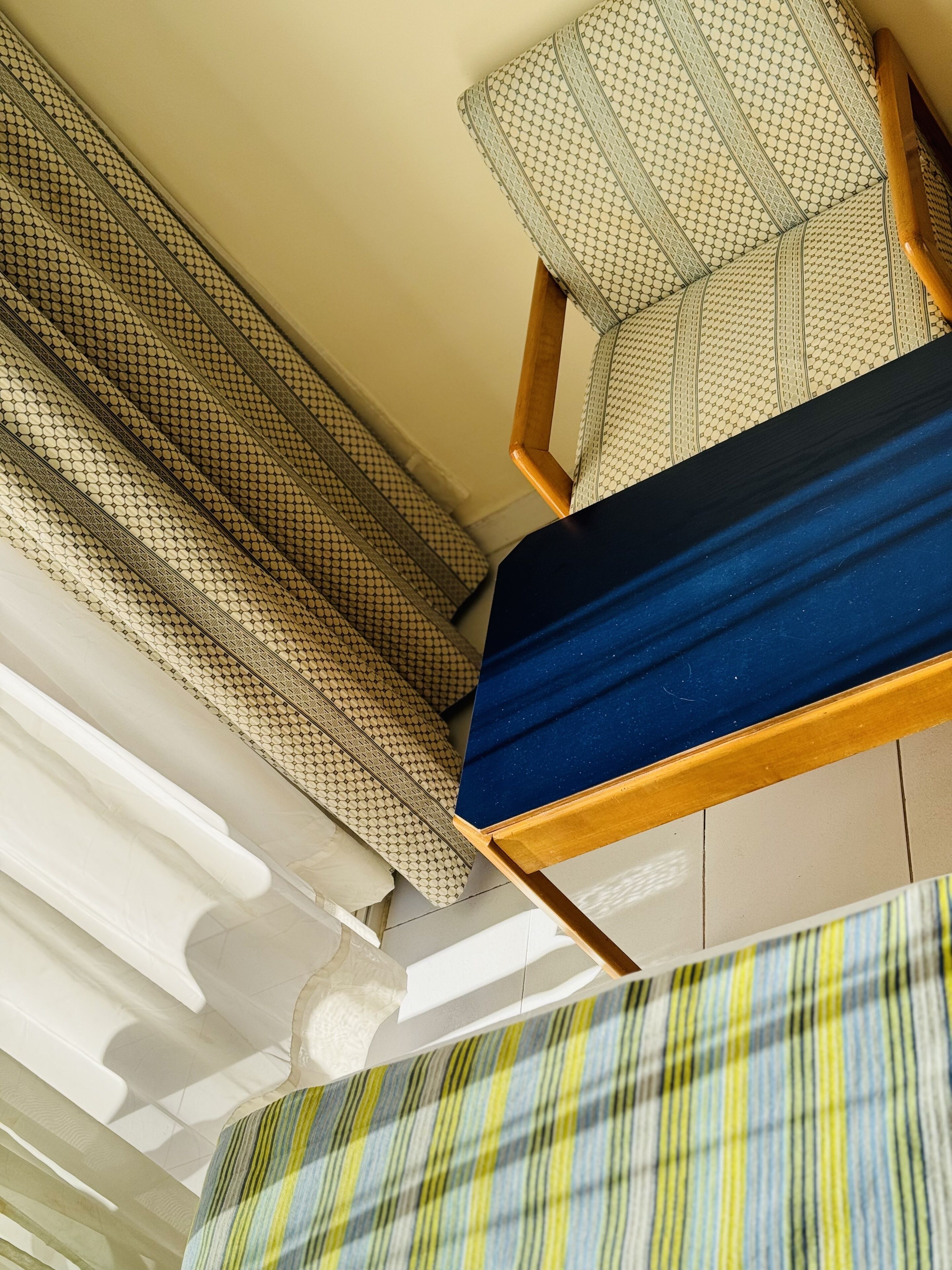 A room with a bed, a chair, and a patterned curtain.