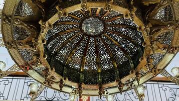 Un lustre élaboré, orné de motifs métalliques complexes et doté de plusieurs lampes suspendues.