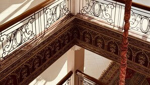 A multi-level interior with ornate railings, a central seating area with yellow chairs, and a patterned floor. - Hotel Idou Tiznit (Tiznit)