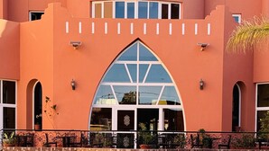 A hotel with a large arched entrance, a swimming pool in front, and a tiled patio area. - Hotel Idou Tiznit (Tiznit)