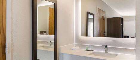 Un baño moderno con dos lavabos, un espejo grande y un perchero para toallas.