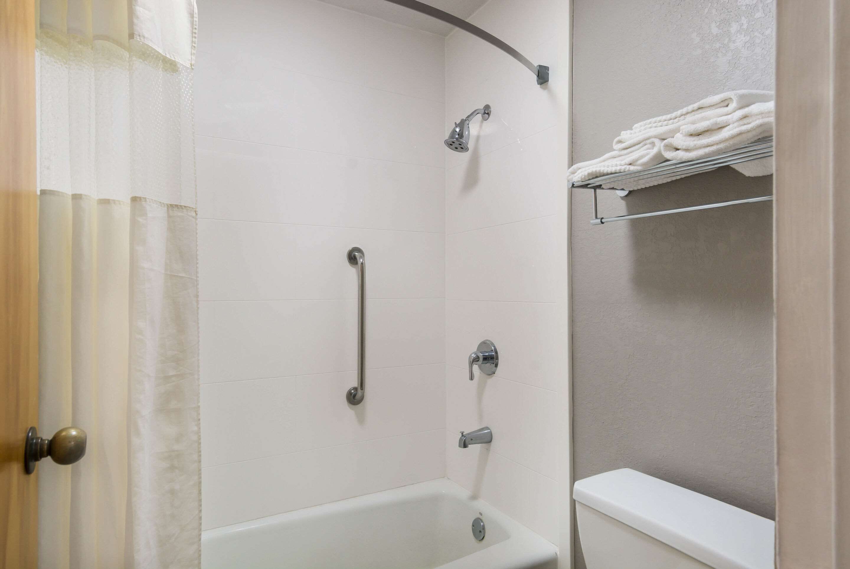 A bathroom with a bathtub, a shower, and a toilet. There is a towel rack with towels on it.